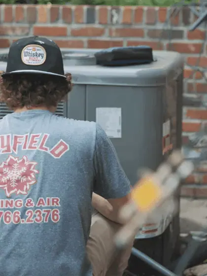A professional technician from Mayfield Heating & Air performing maintenance on an outdoor AC unit, representing a top-rated HVAC company in Tallahassee FL.